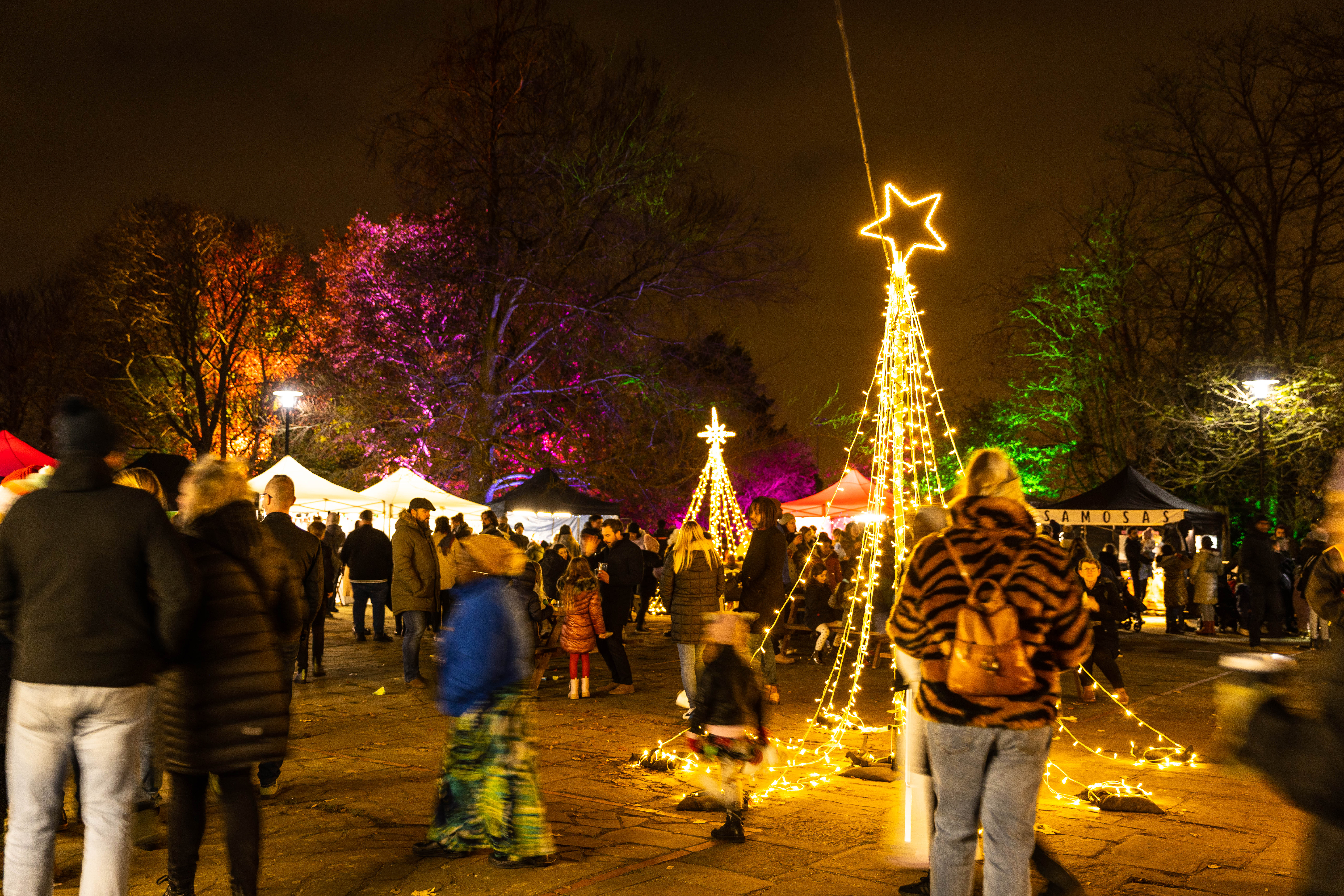 Christmas lights in the background with people walking towards them