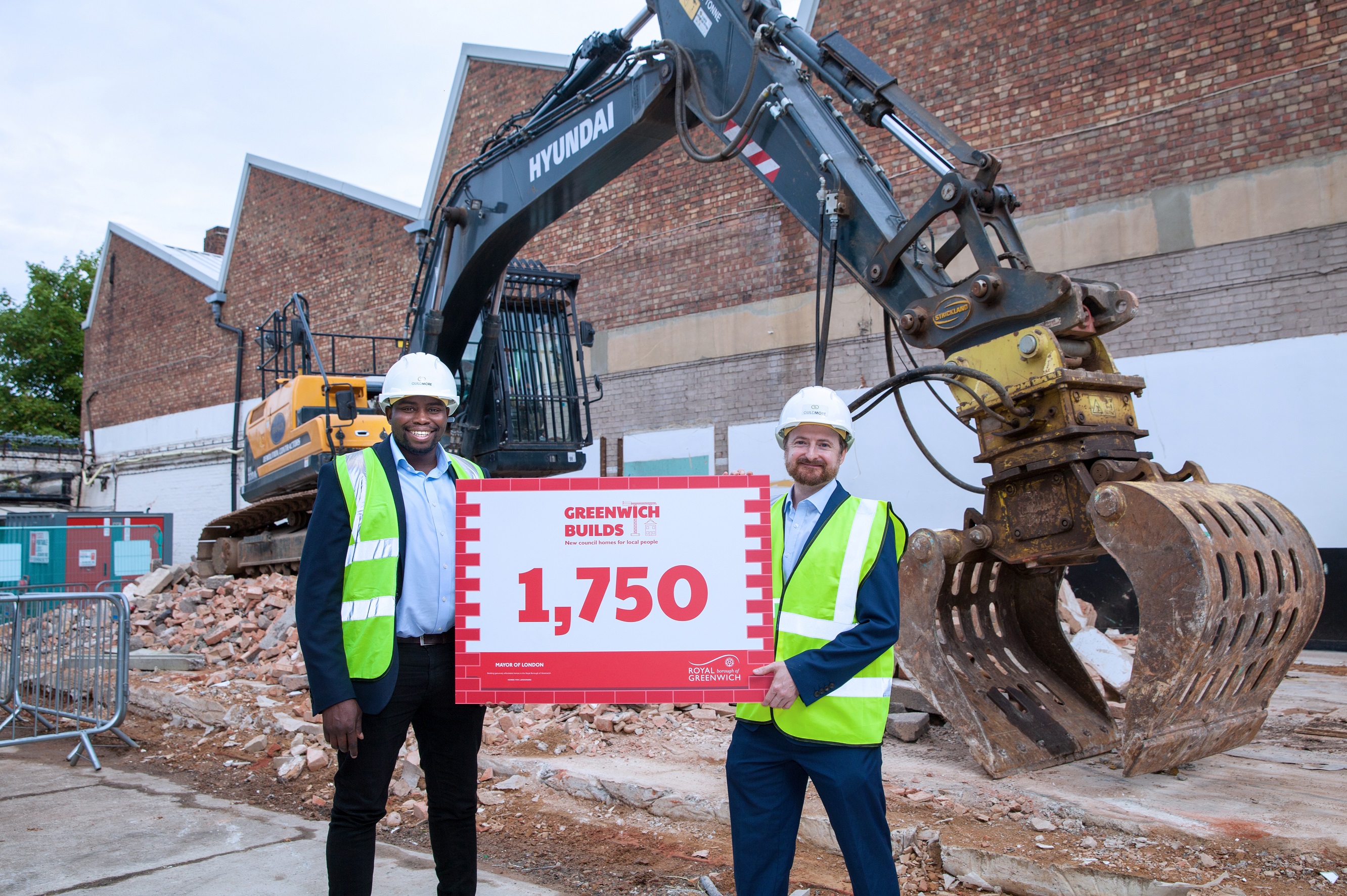 Cllr Anthony Okereke and Cllr Aidana Smith stand in front of a crane in protective clothing, holding a sign that bears the number 1750