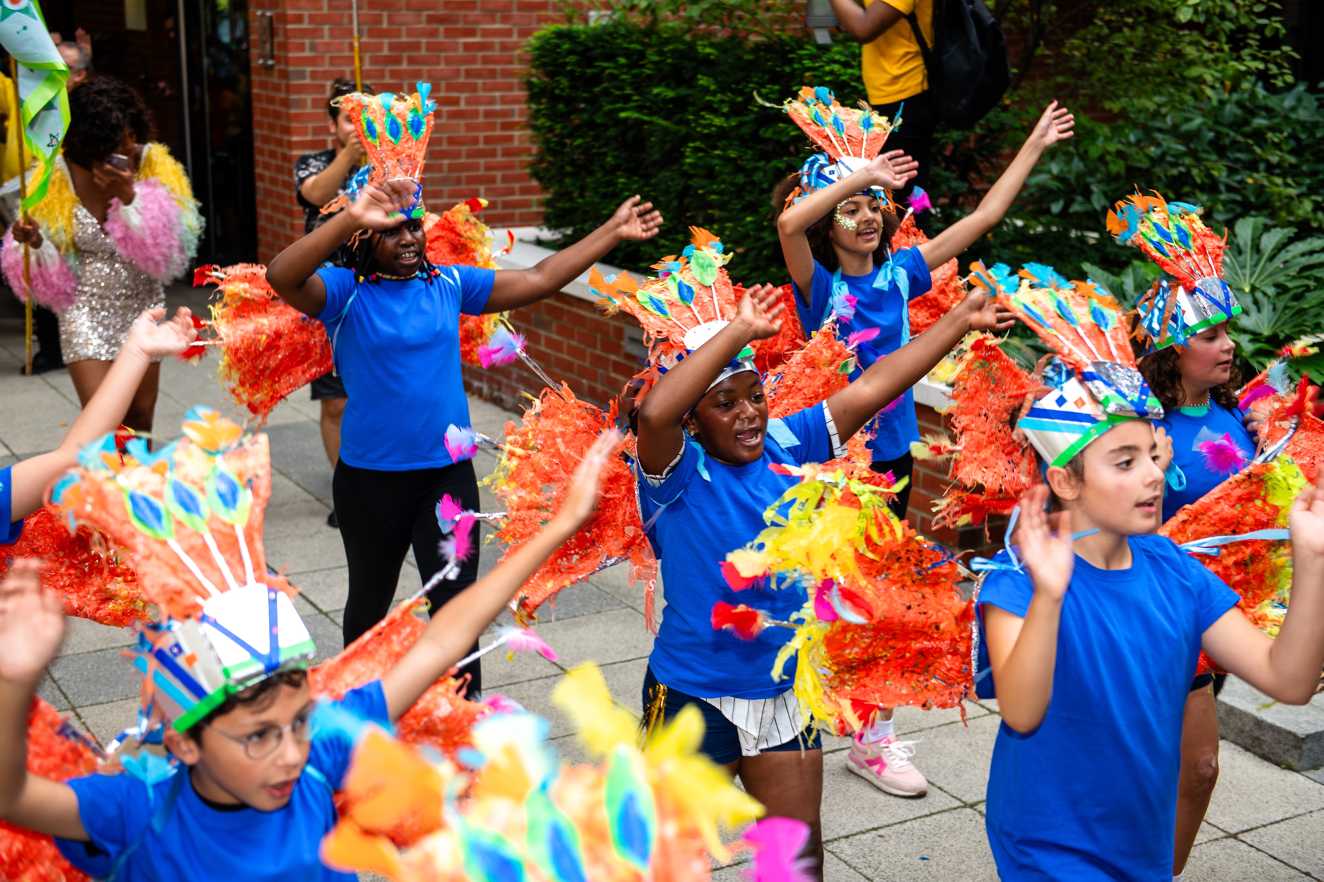 A group of primary school schildren in blue t shirts and carnival head wear at Woolwich carnival