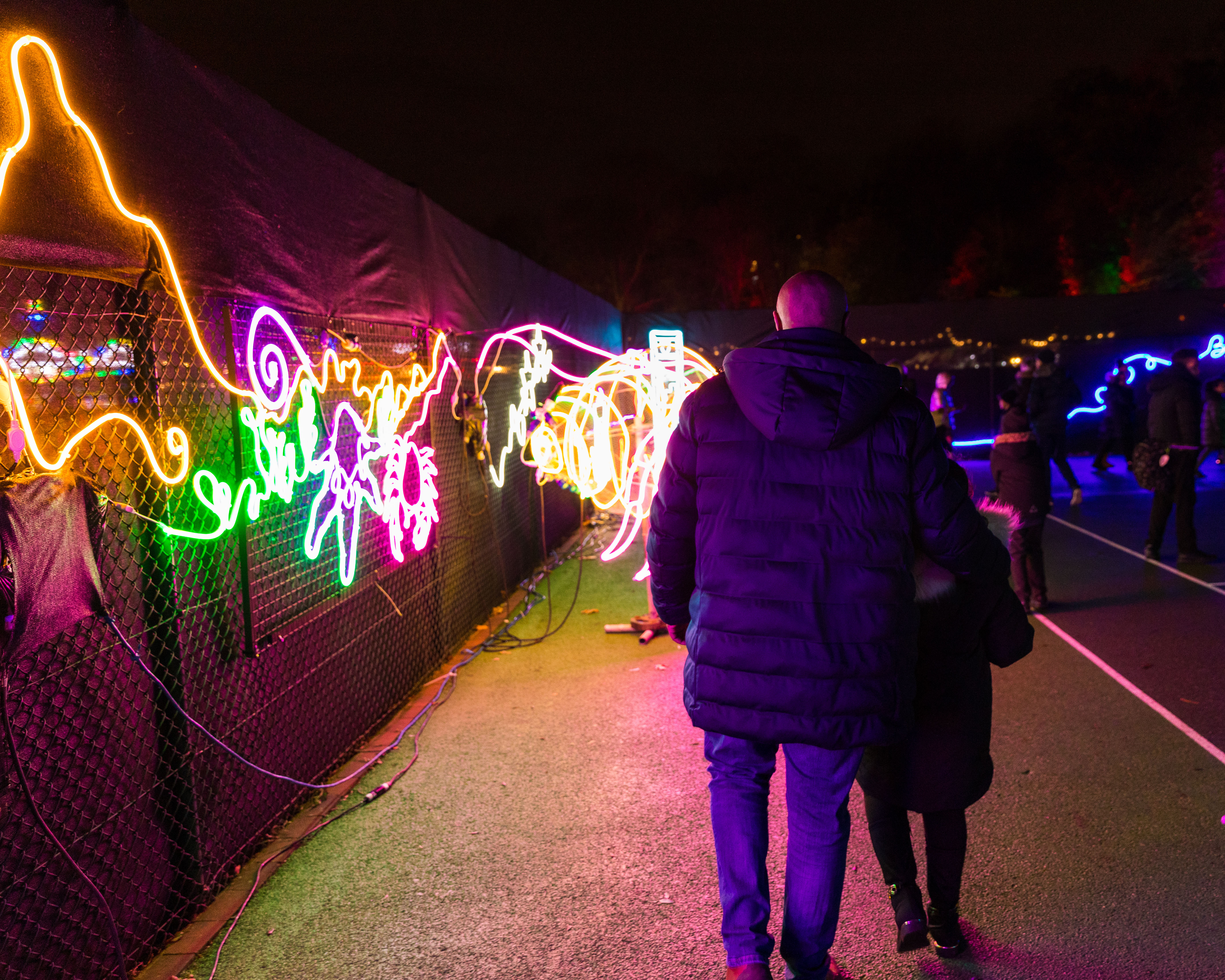 Cllr adel khaireh walking past neon lights at night