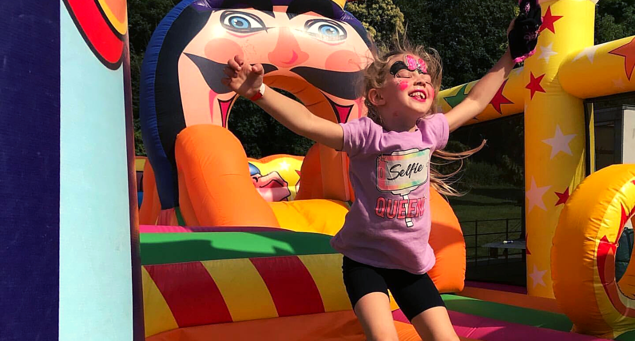 Young girl with face paint jumping in a bouncy house