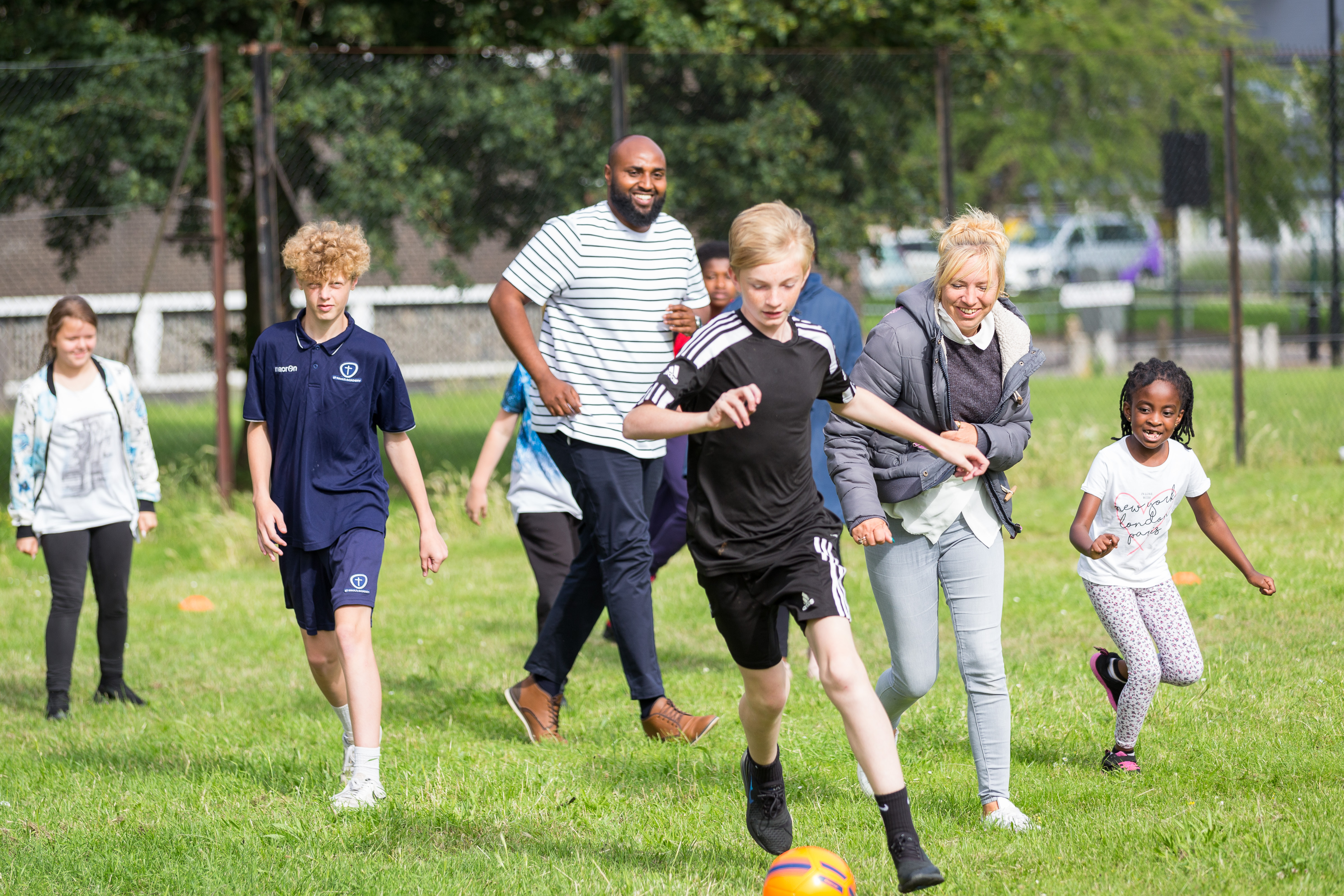 A group of adults and children playing football