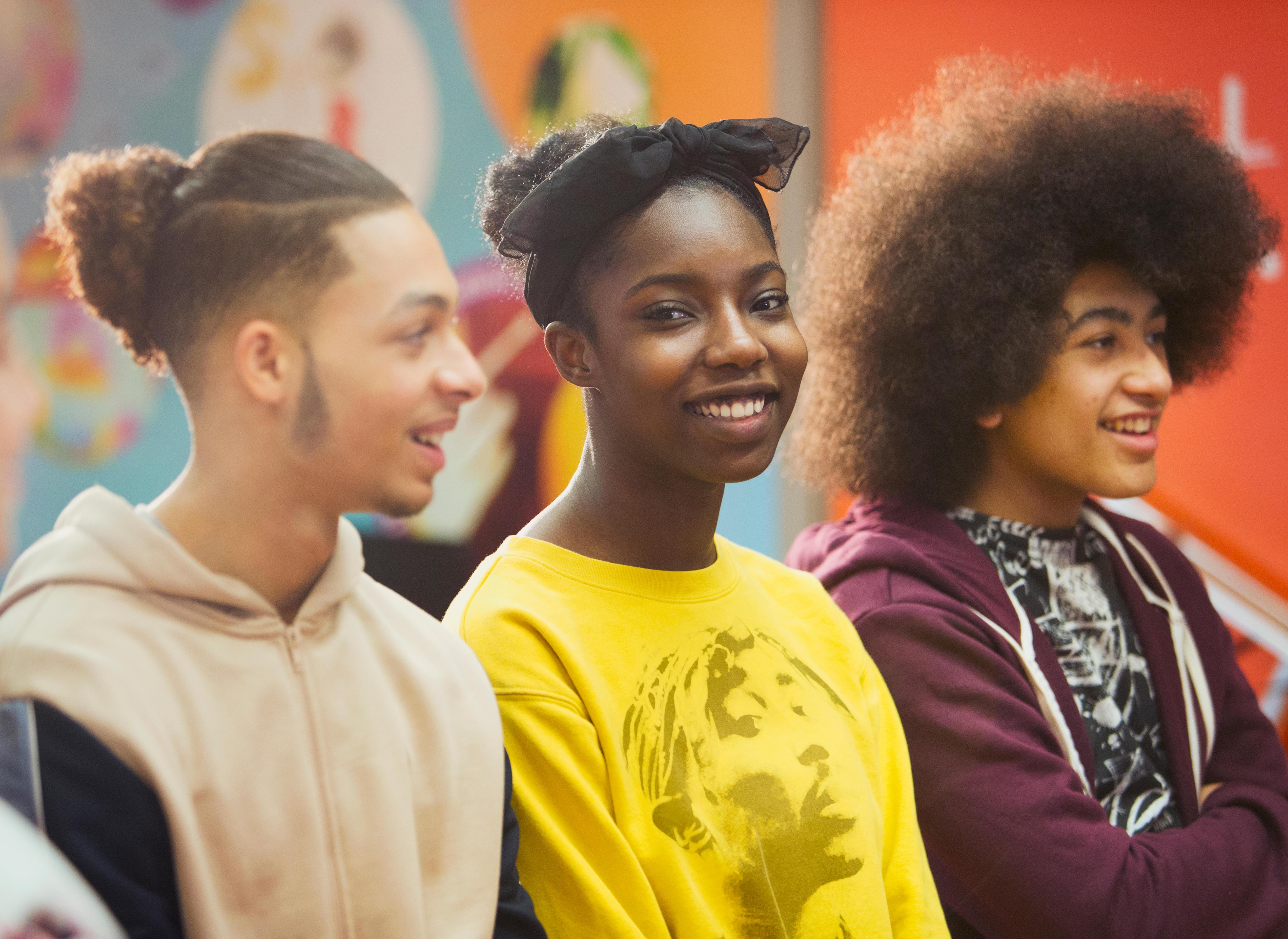 Three teenagers, one smiling directly at the camera