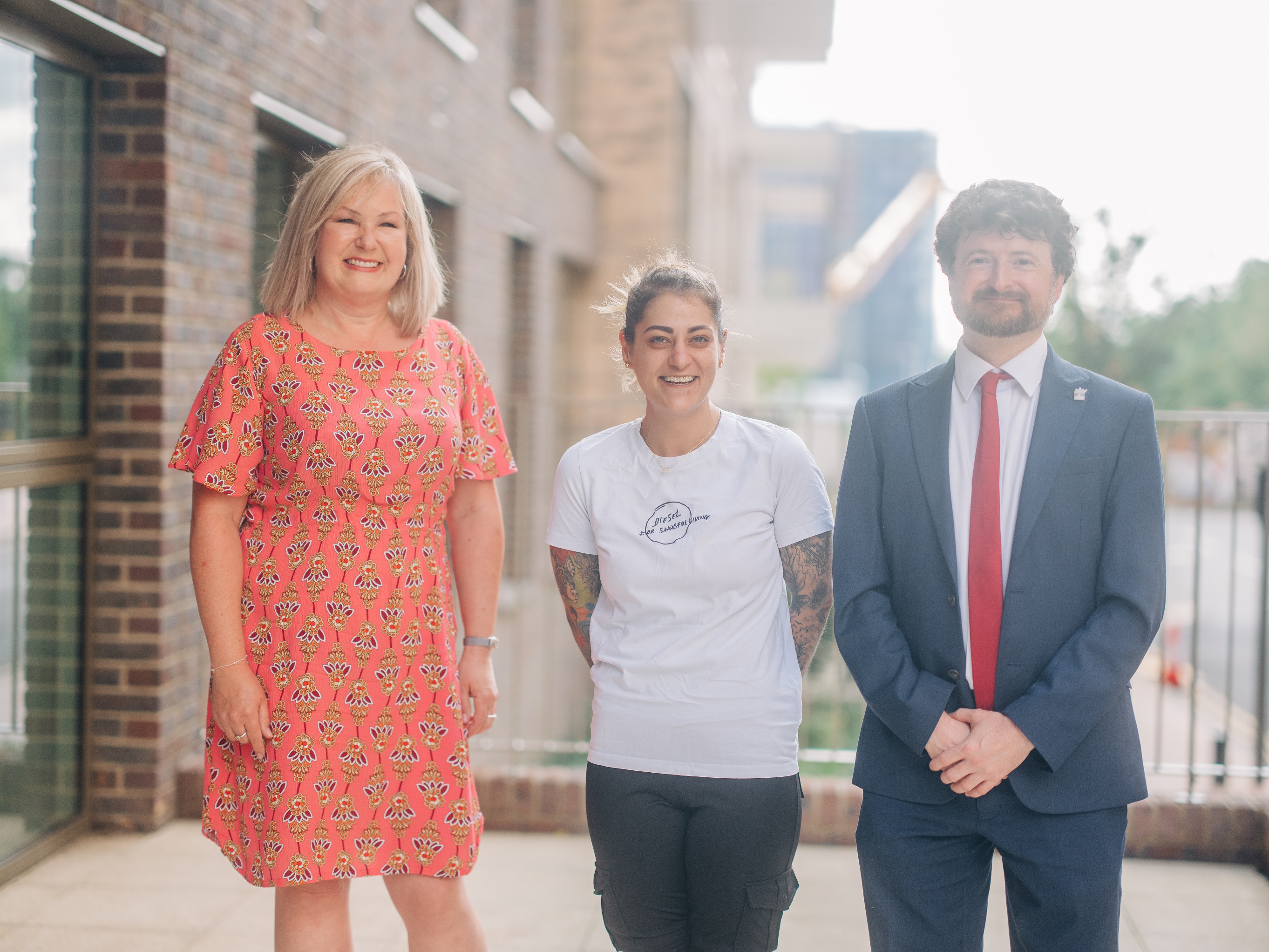 Cllr Sandra Bauer, resident Deborah and Cllr Aidan Smith stood smiling side by side on the balcony of a new affordable home