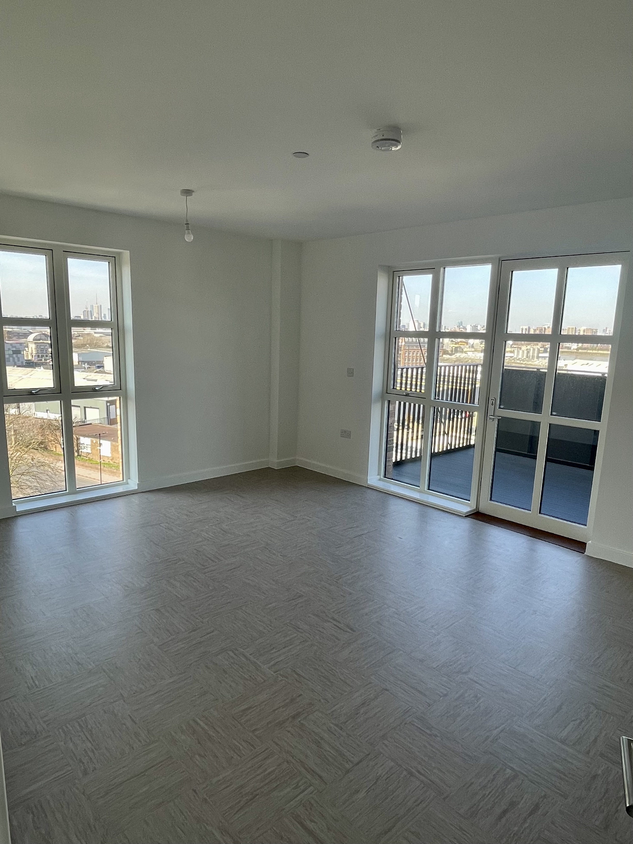 A new unfurnished living room with a door leading out to the balcony.