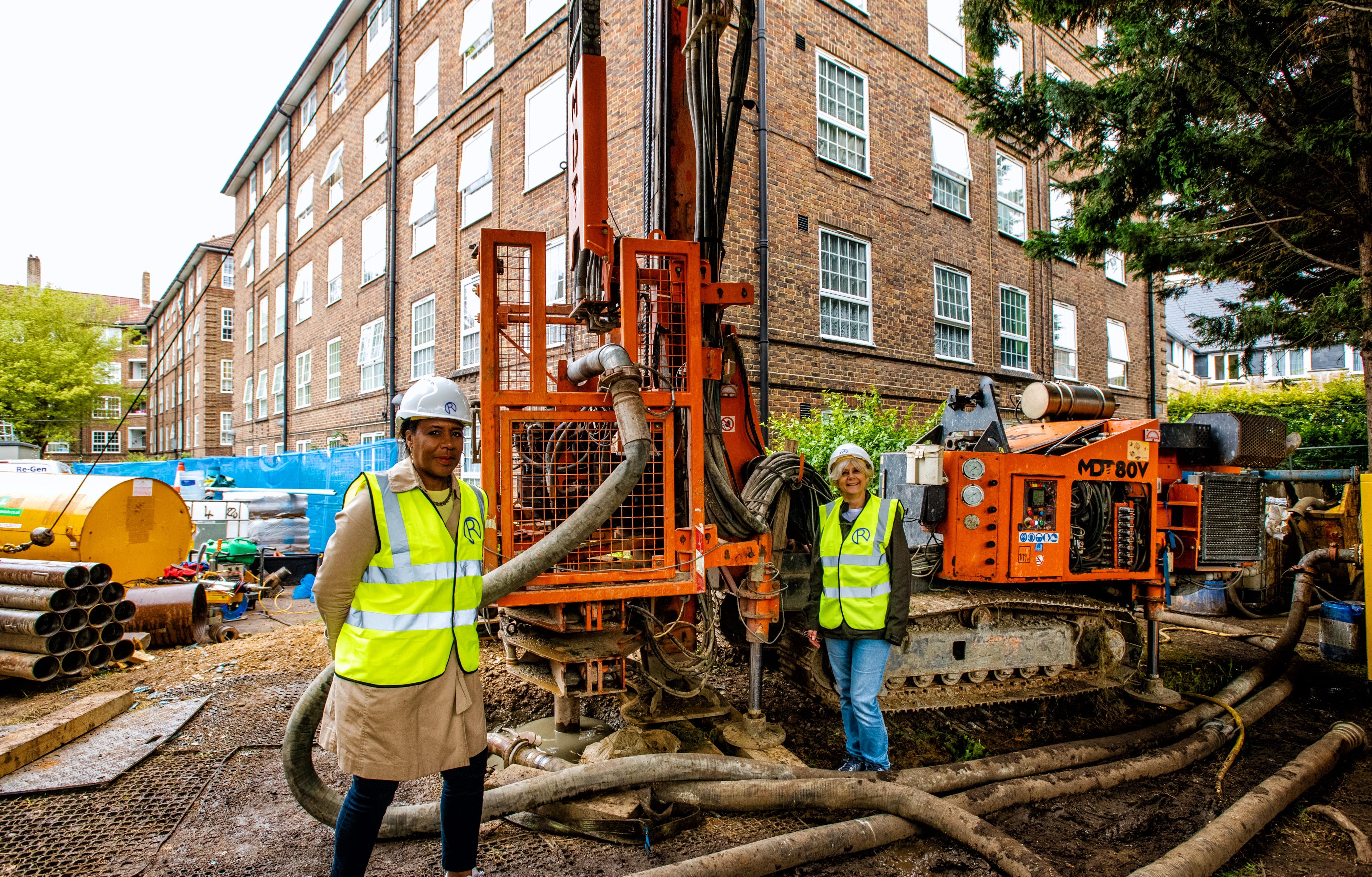 Cllrs Denise Scott-McDonald and Sarah Merrill witness the first borehole drilling at Ernest Dence Estate, Greenwich, to fit highly innovative water-source heat pumps