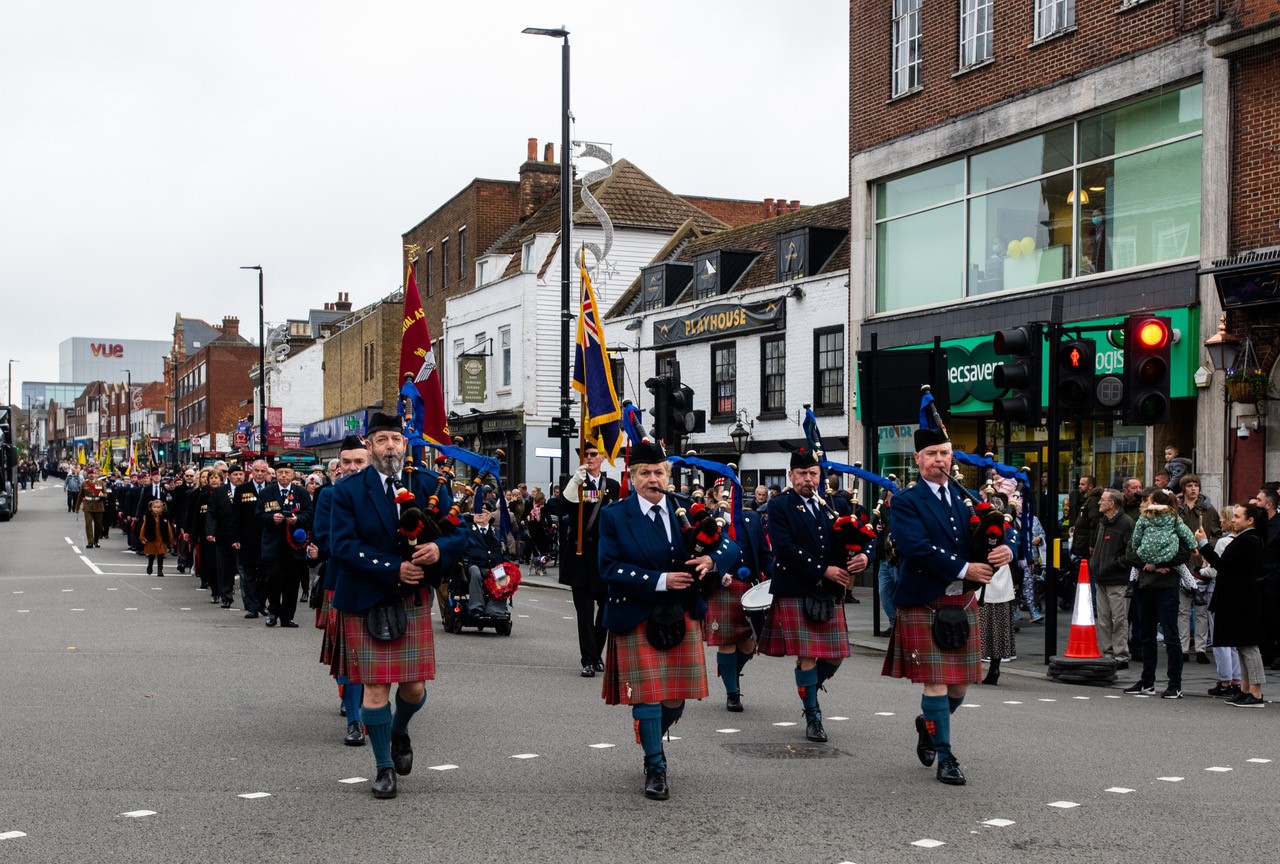 Remembrance Weekend parade being led by men wearing kilts playing bagpipes