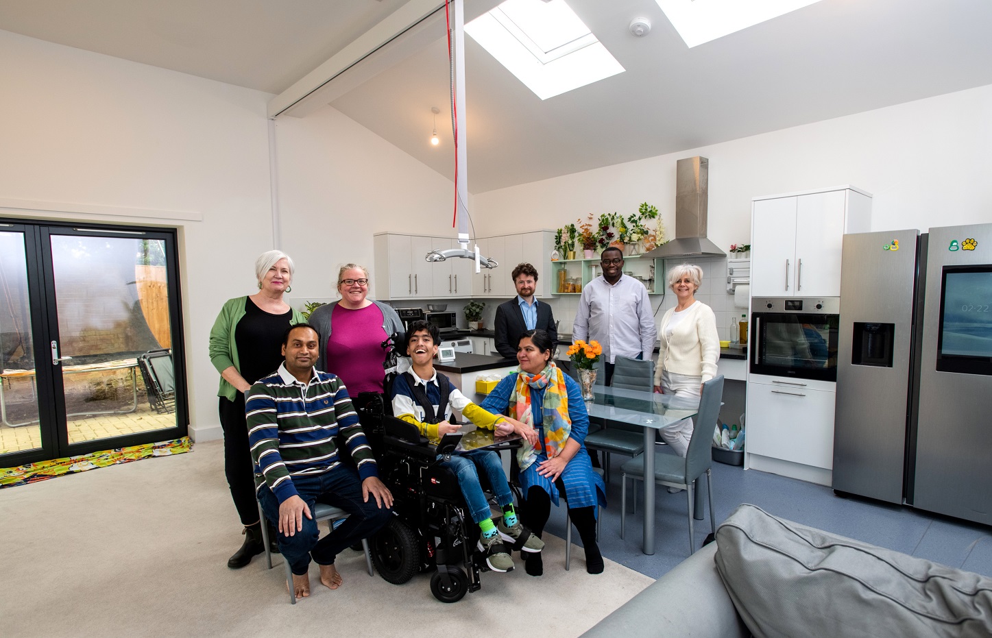 Councillors and tenants smiling in living room of wheelchair adapted council home.