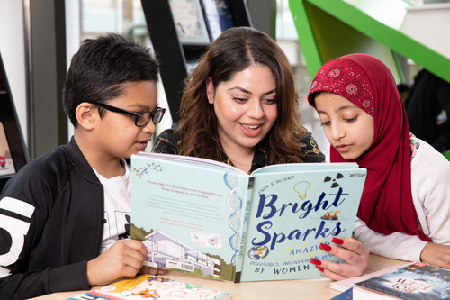 Mom and two children reading a book.