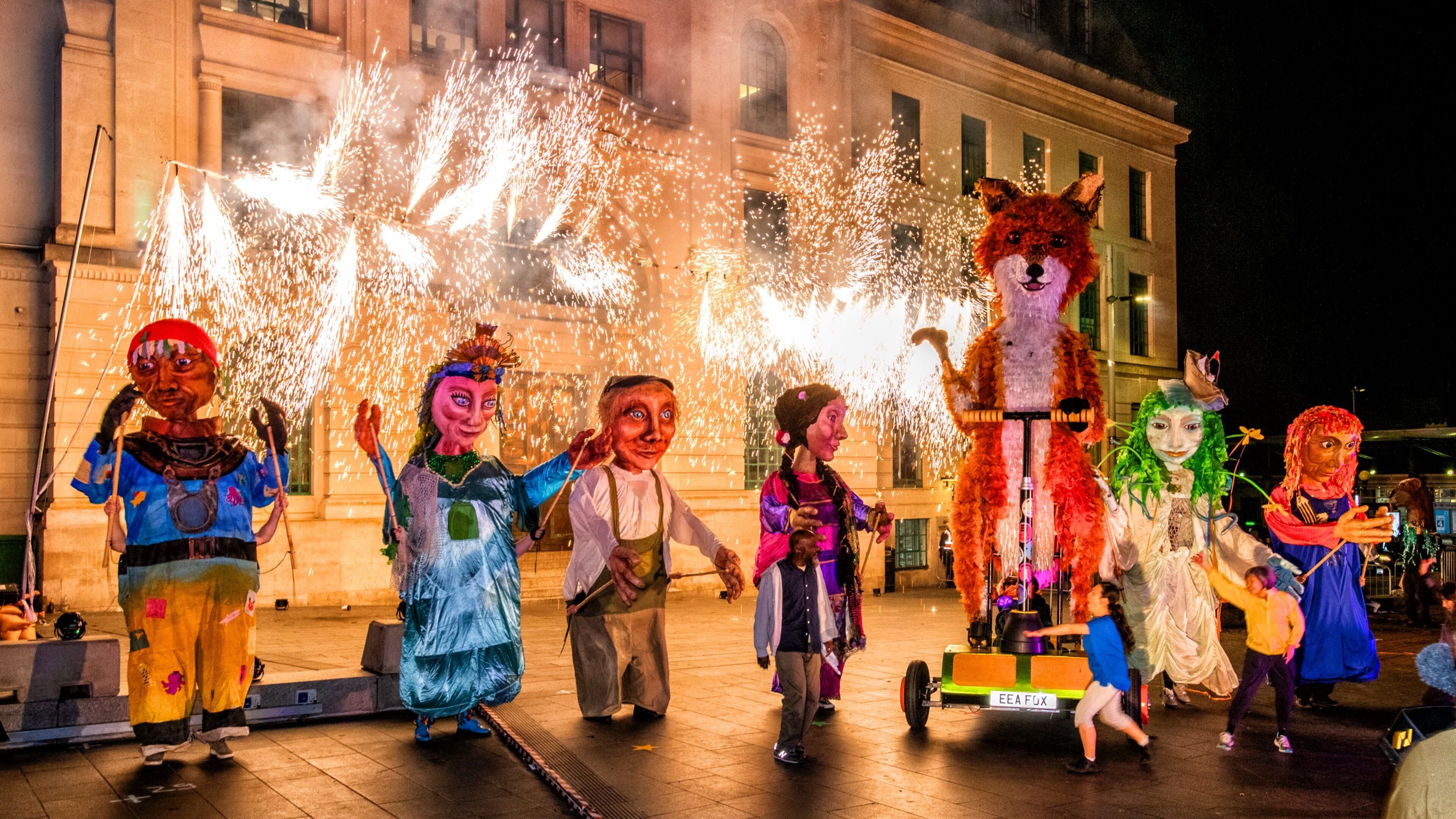 Seven giant puppets with sparks flying behind them