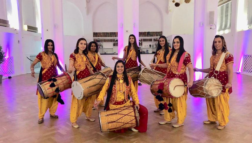 All female Bhangra collective. Eight women wearing Sari's, holding drums.