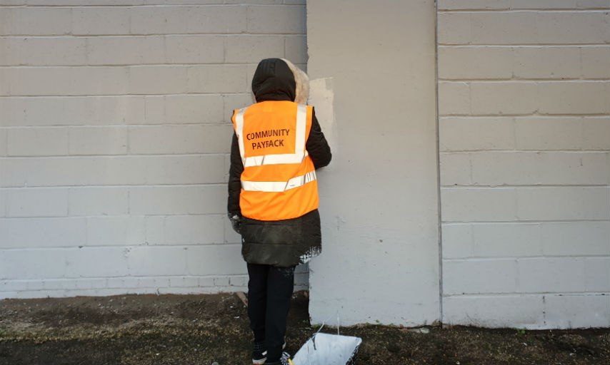 Community payback service user painting a wall