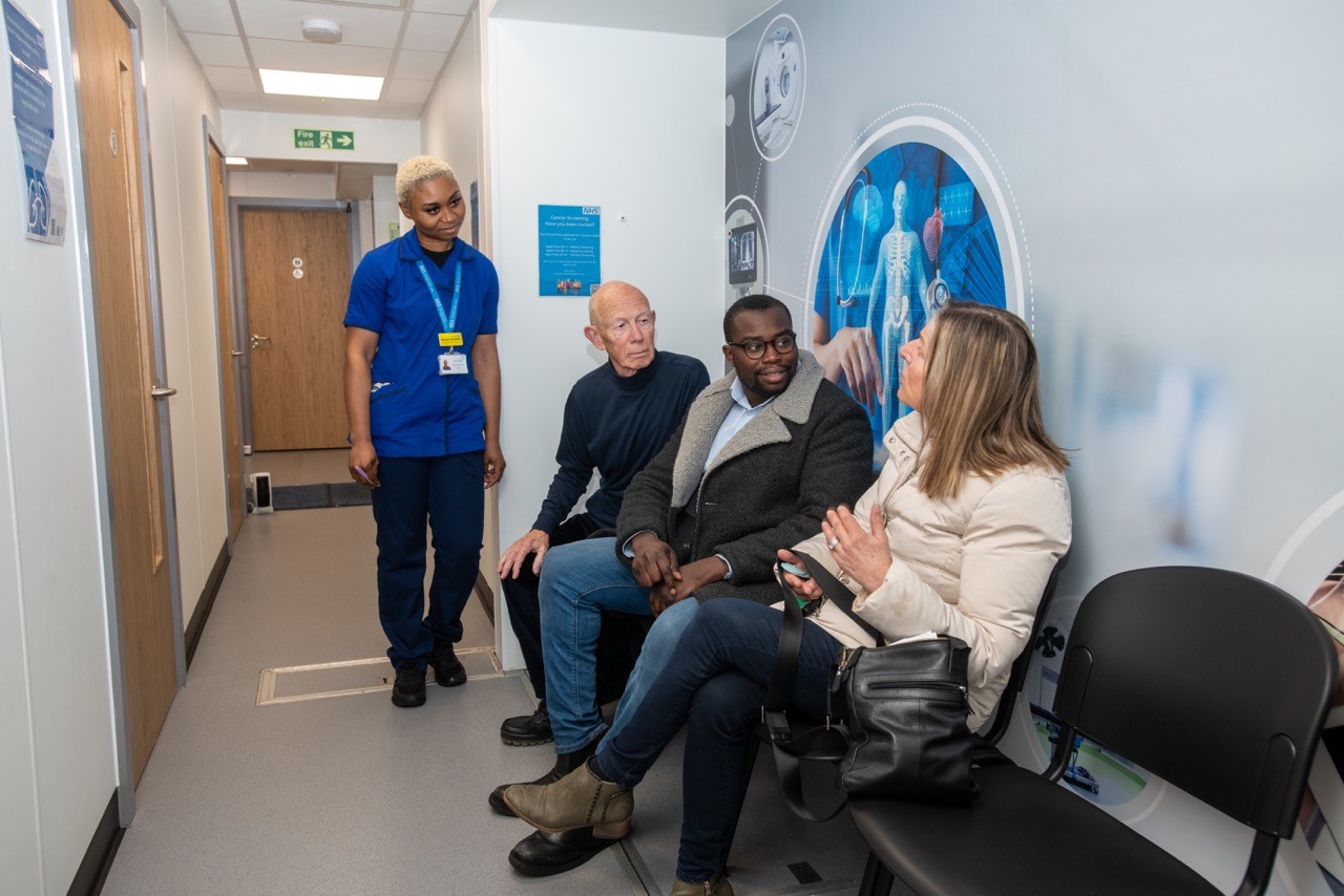 Cllr Anthony Okereke speaking to two people getting their health checked