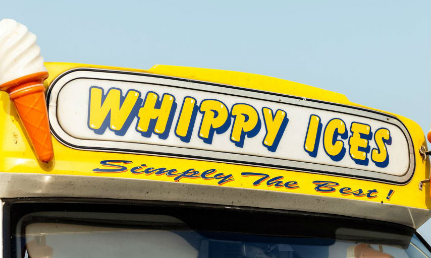 Yellow ice cream van with ice cream cone emblem.