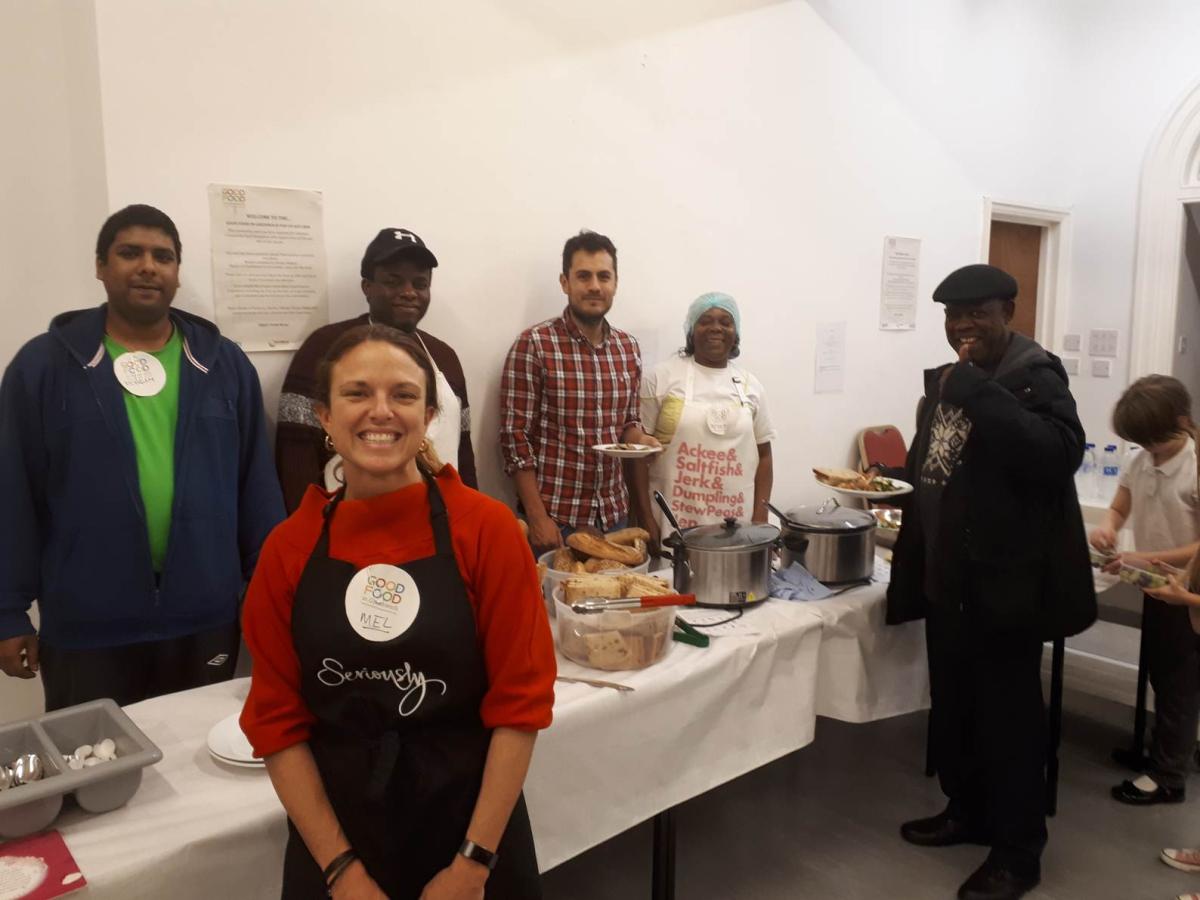 Good Food in Greenwich Community Kitchen - the image shows people putting themselves plates while smiling to camera, with staff also smiling at the camera