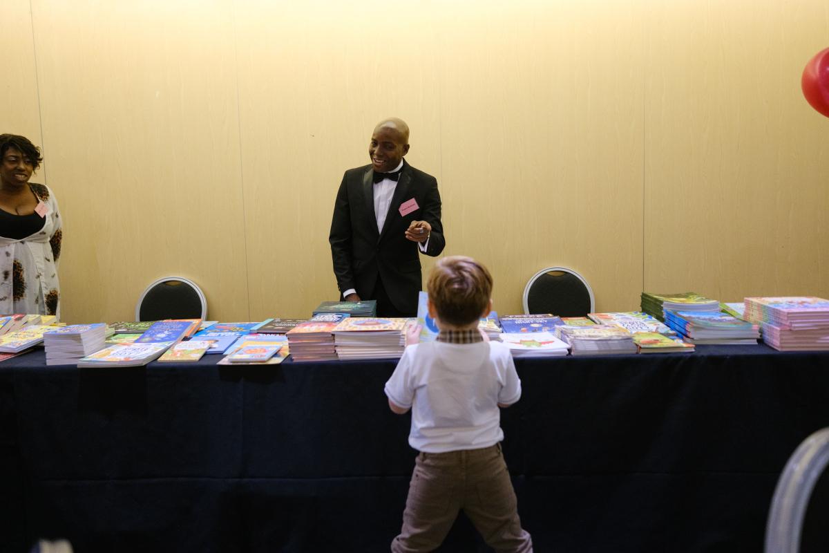 Back of a child talking to someone at book shop stall.