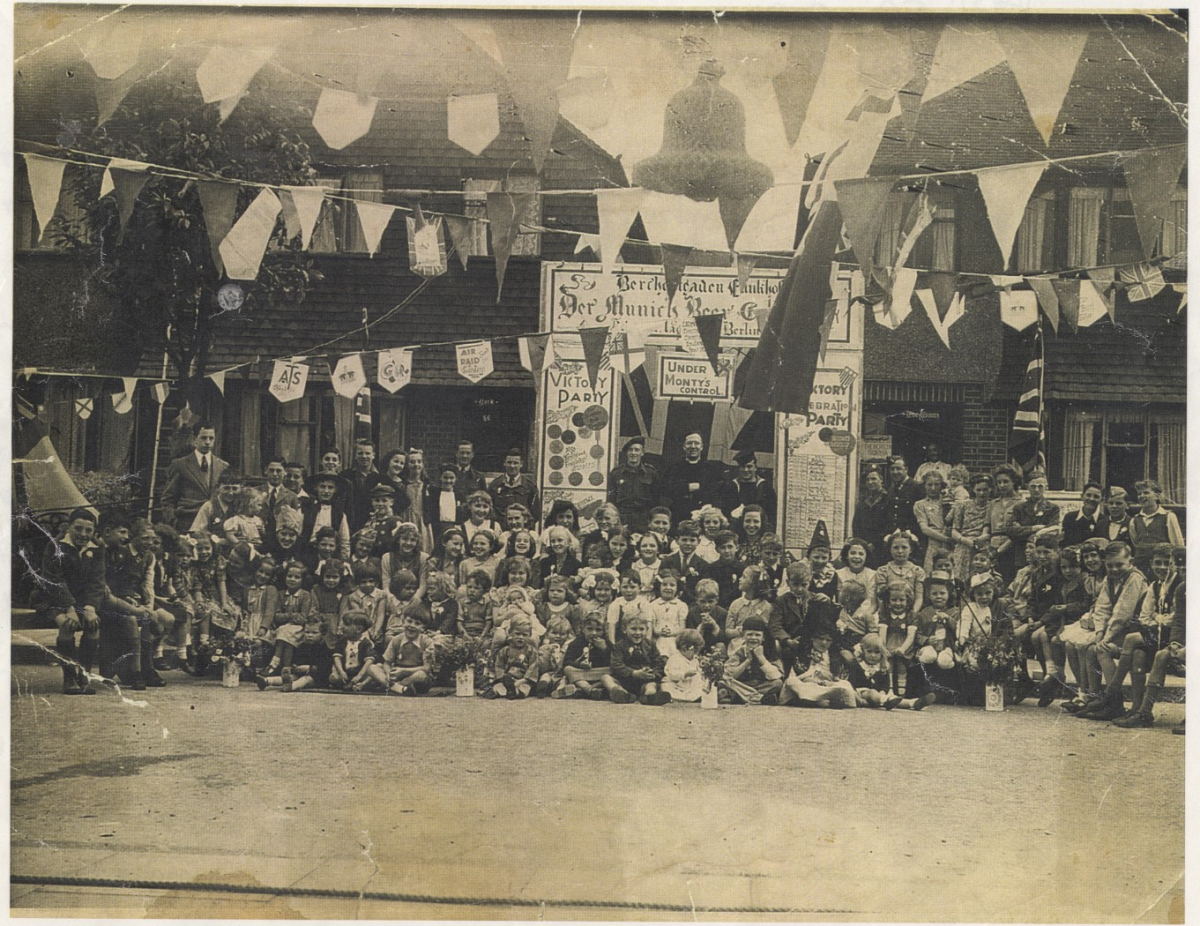 A group of people in front of a row of houses at a street party in 1945