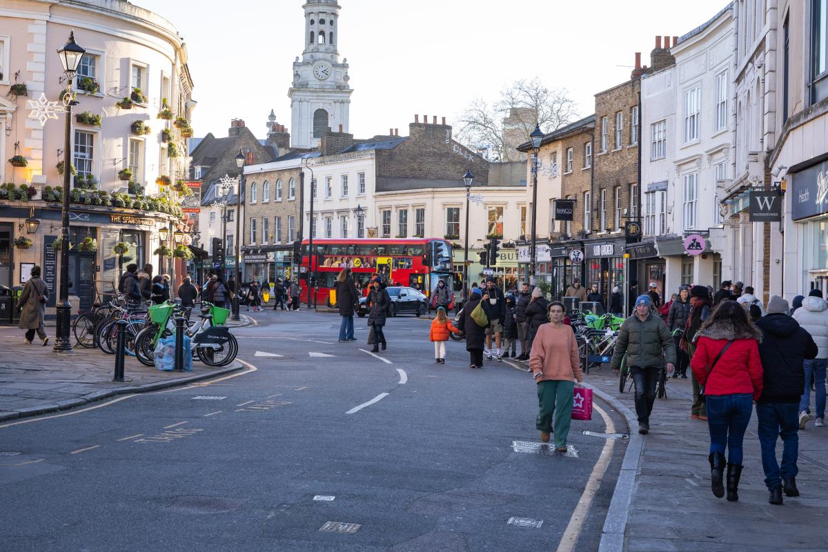 Photo of Greenwich Church Street during the day with people on both sides of the road and a red bus in the distance