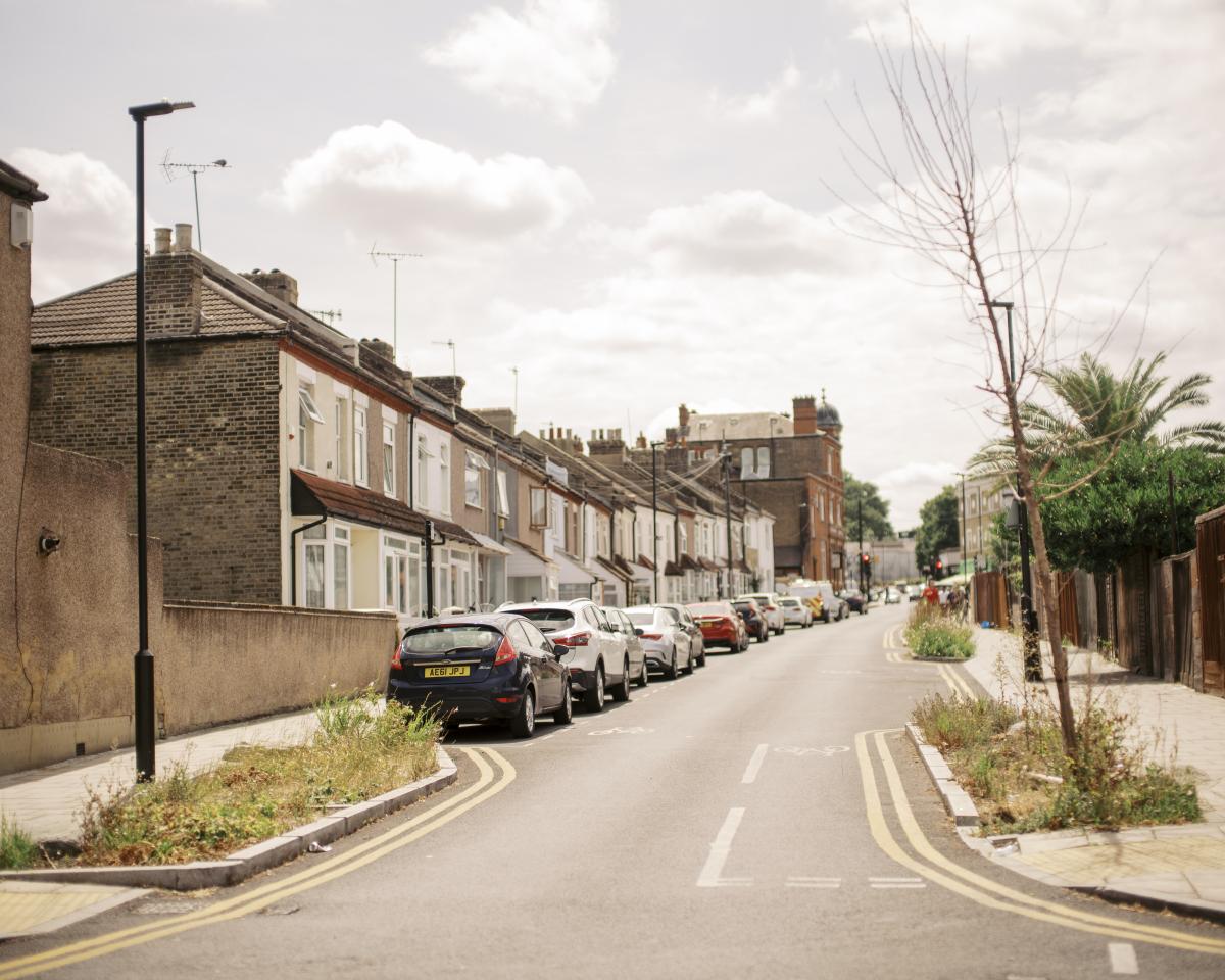 A street with green grass in the foreground and parked cars in the distance