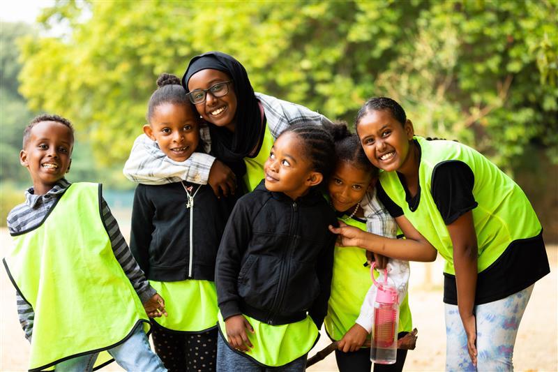 Five children in hi-vis vests with adult coach 
