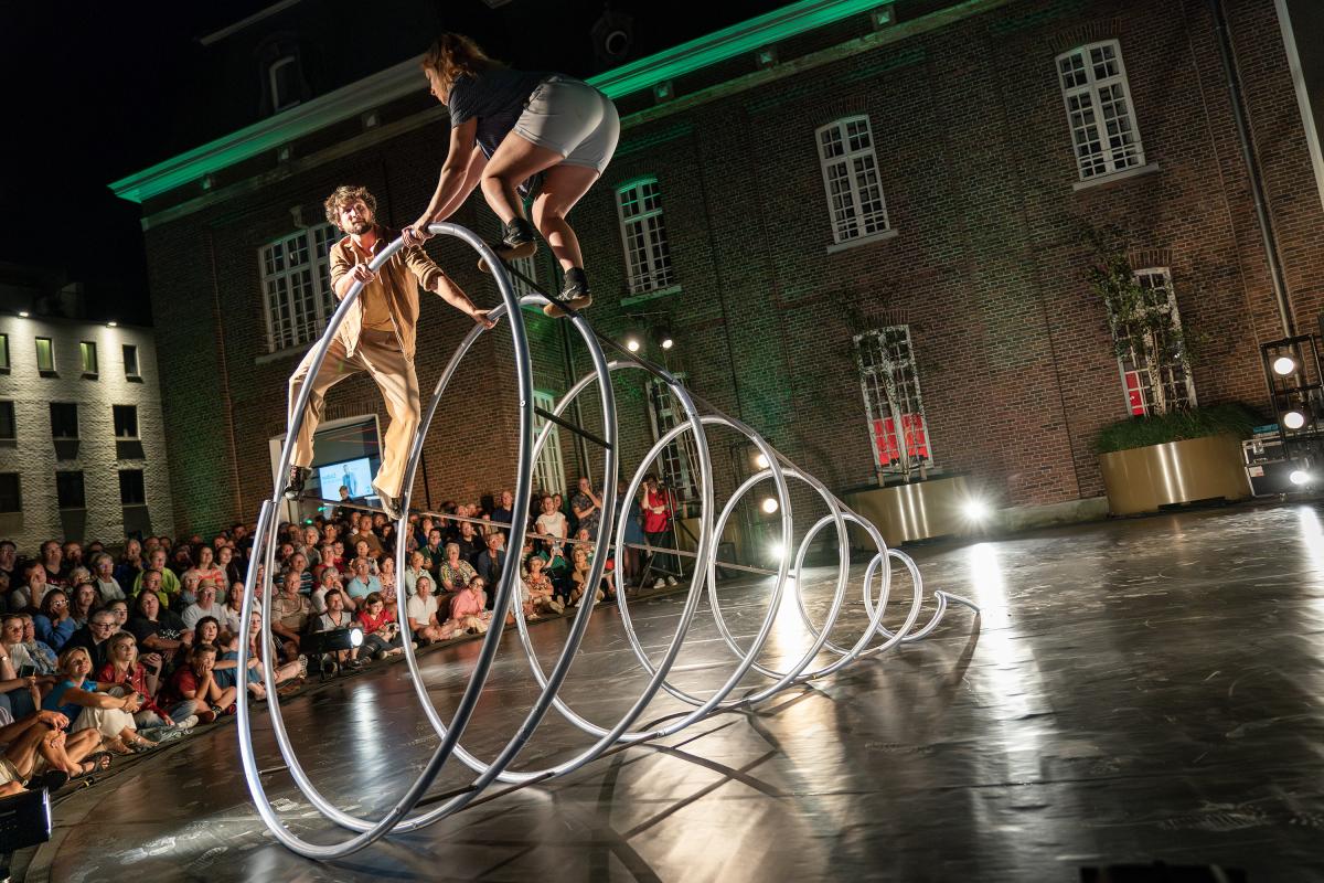 Performers on a metal frame in front of a crowd.