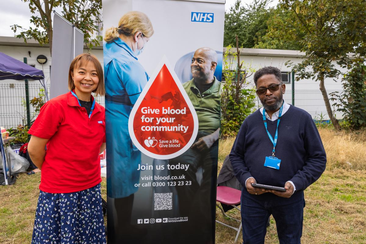 NHS Blood and Transplant staff posing with their 'Give Blood' banner