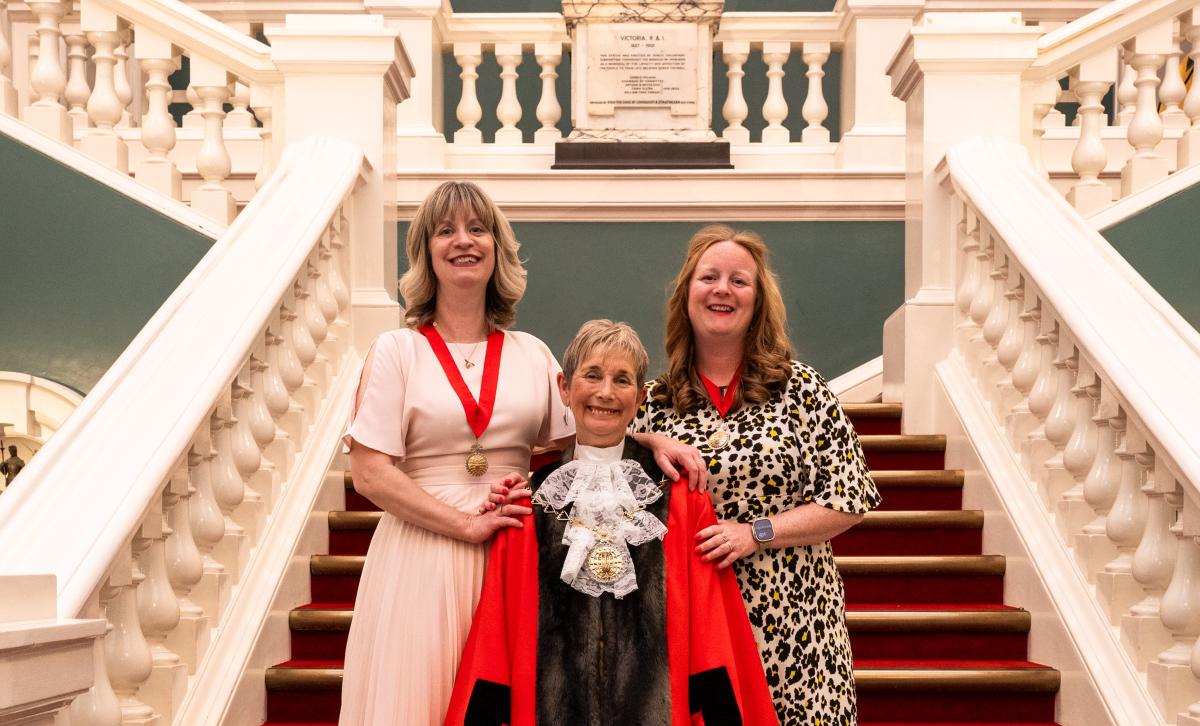 Mayor Cllr Linda Bird in full ceremonial dress standing on the steps of the Woolwich Town Hall with her daughters on either side of her.
