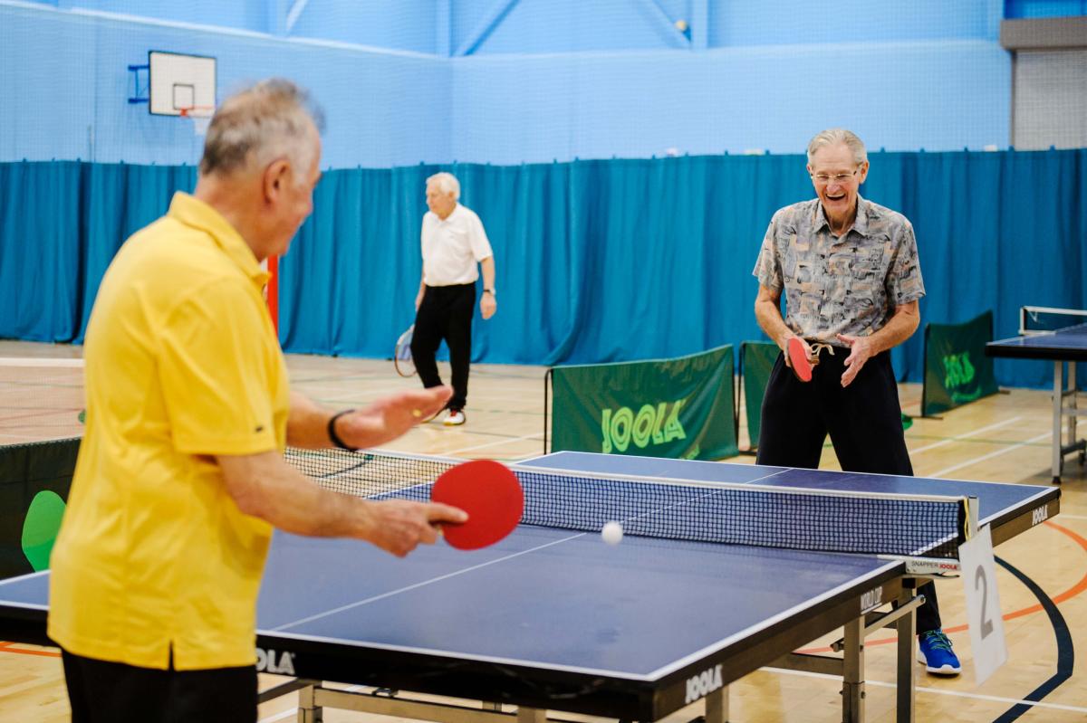 Image showing two men being physically active and playing table tennis