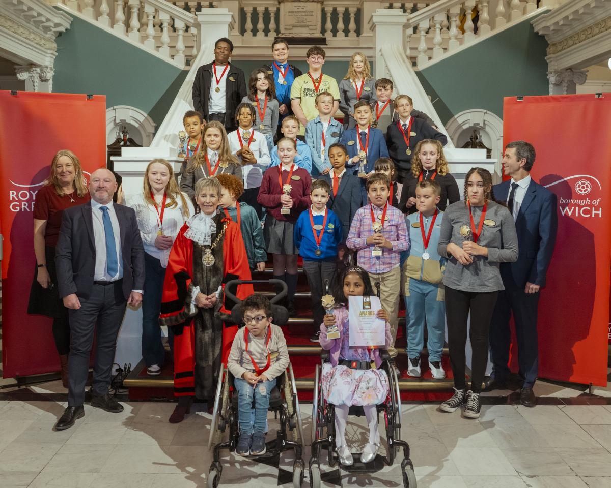 A group of students and dignitaries stand at the stairs in Woolwich Town Hall