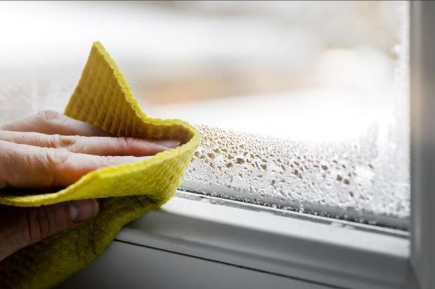 condensation being wiped away from an indoor window with double glazing.,