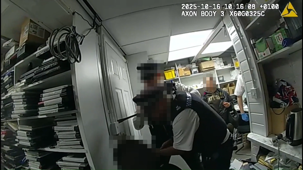 A screenshot of bodycam footage of 2 police officers opening a secret room