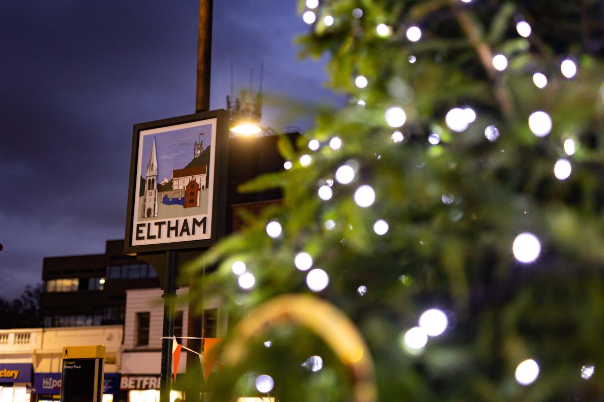 A close up Christmas tree next to a sign that says 'Eltham'