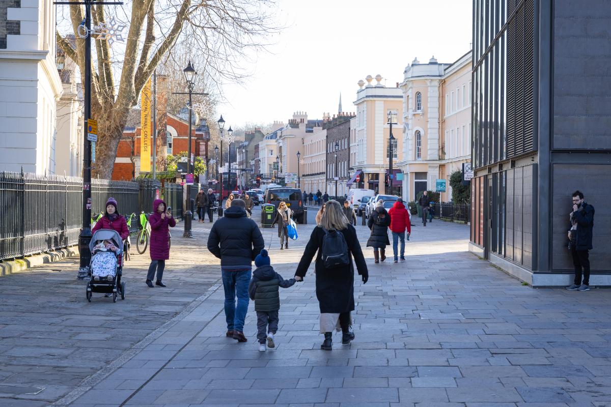 Image of Greenwich town centre, family walking hand in hand and more people walking in the background