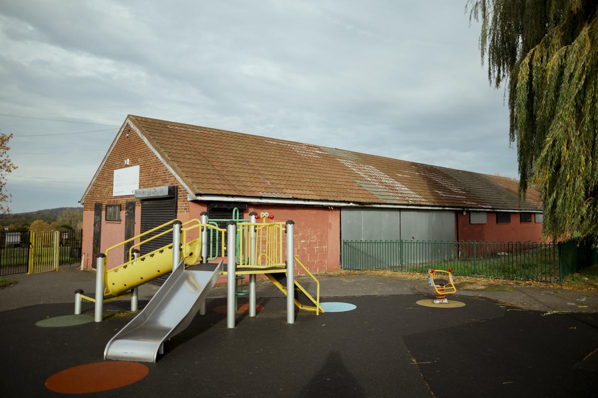 A large brick building, with a playground in front of it.