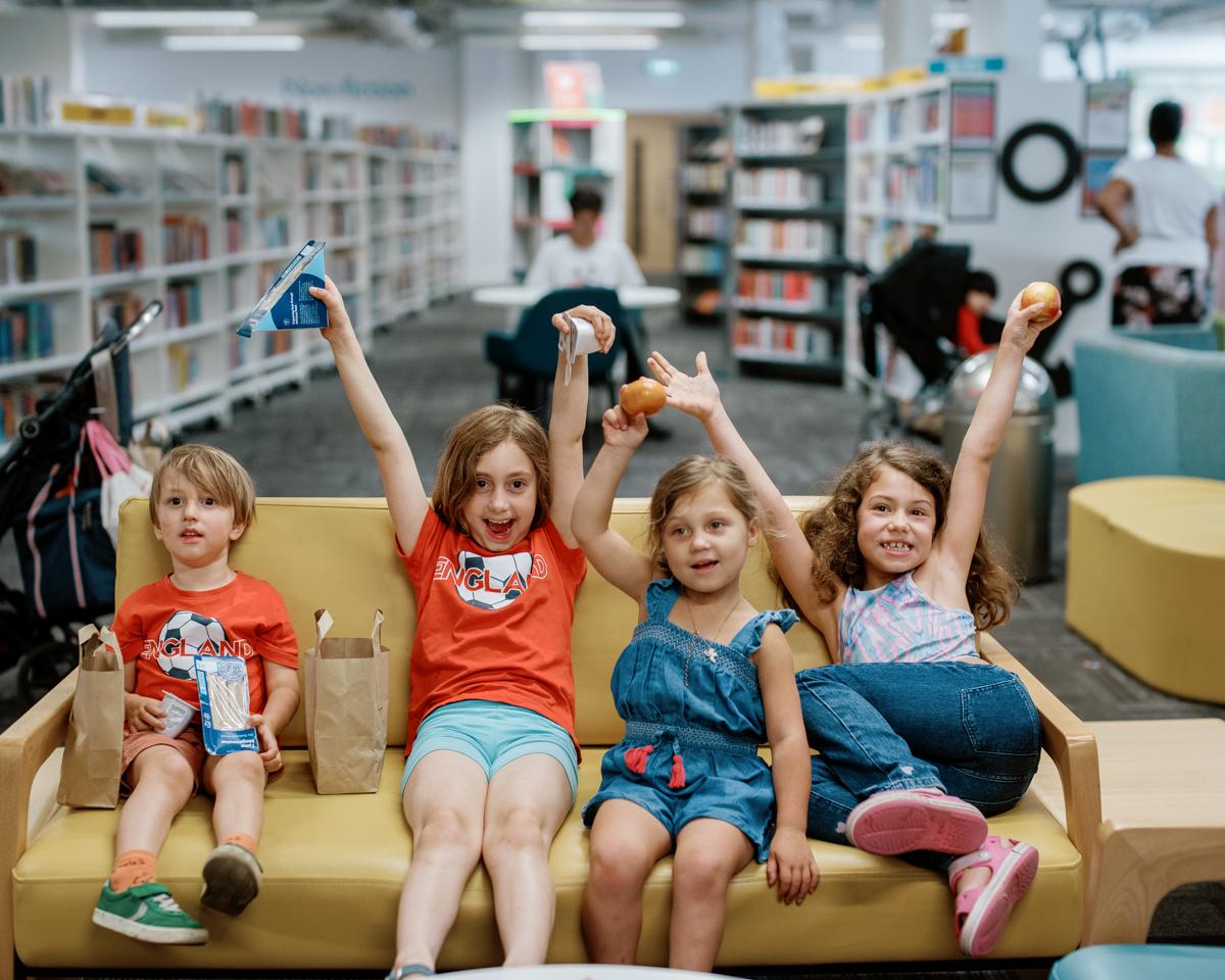 Kids with hands in the air holding their packed lunch