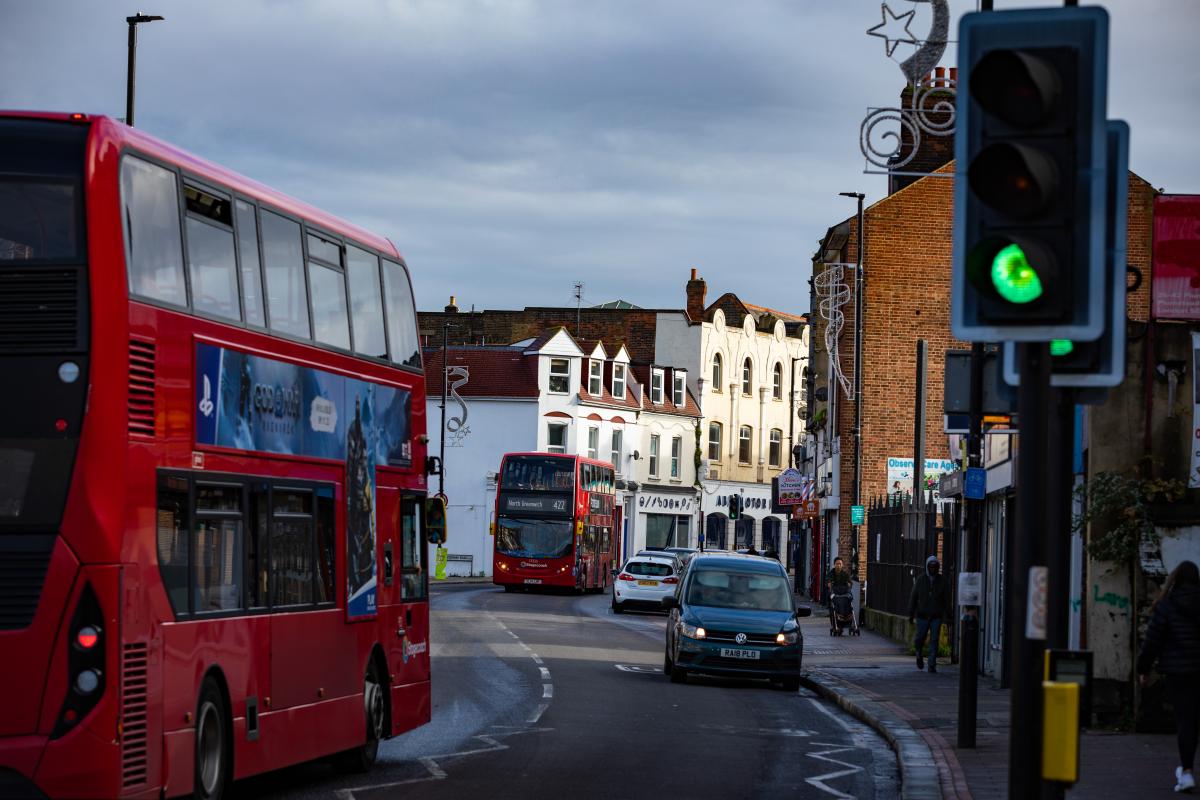An image of two cars and two buses on Plumstead High Street.