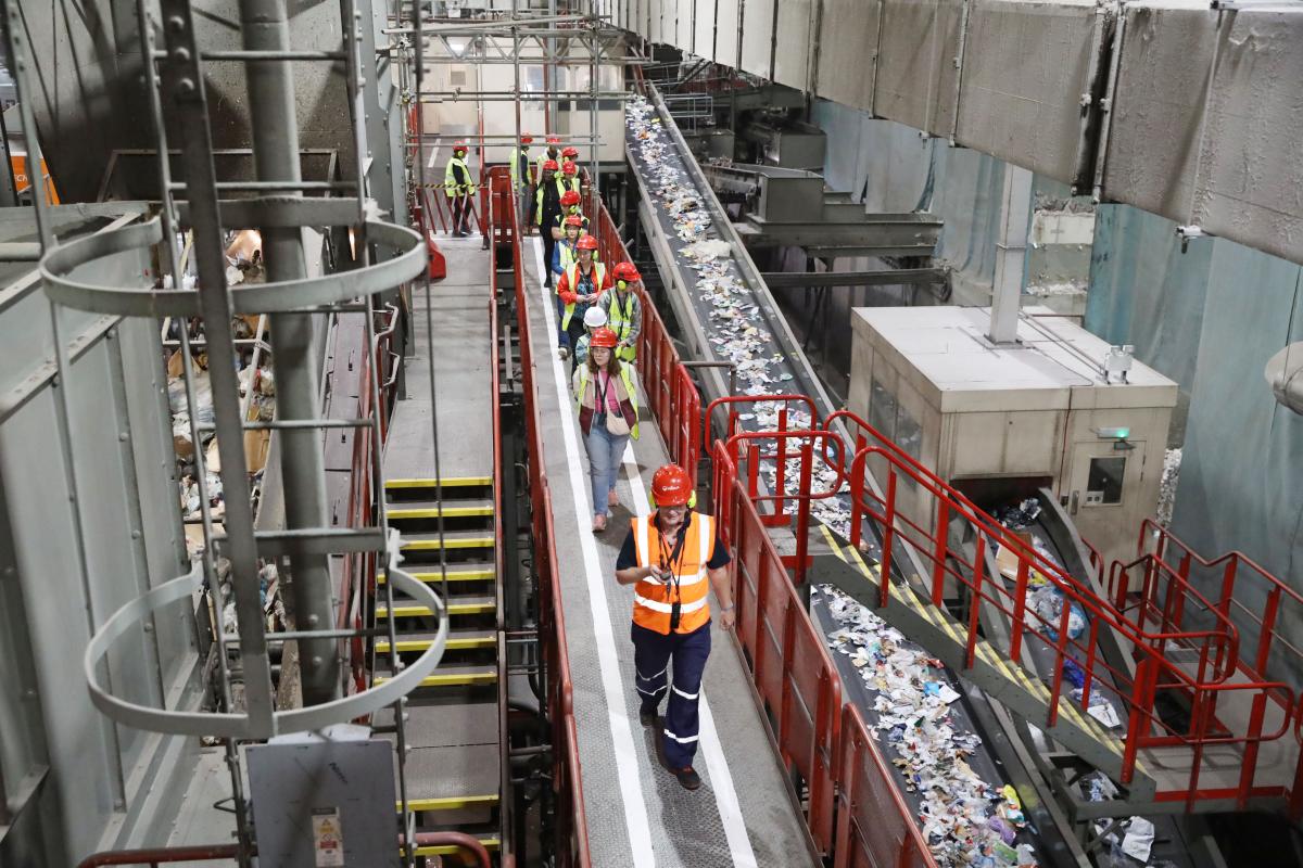 A large room made of metal, with a conveyor belt sorting recycling