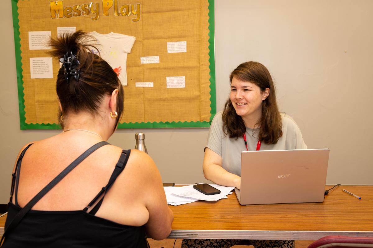 Resident seeking support at Advice Hub in Greenwich, friendly advisor smiles at resident, resident is faced away from the camera