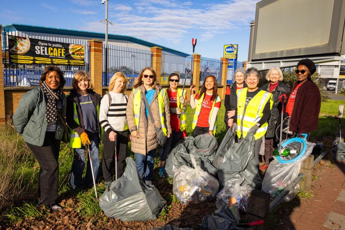 A group of people wearing high vis vests and holding plastic sacks full of waste they have collected