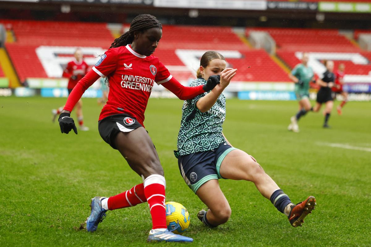Two women playing football at the Valley in Charlton. One is wearing a red Charlton kit and the other wears a green Sunderland kit.