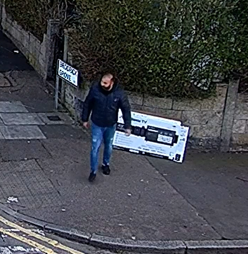 An image of a man drumping an empty TV package box on the side of the pavement and walking off