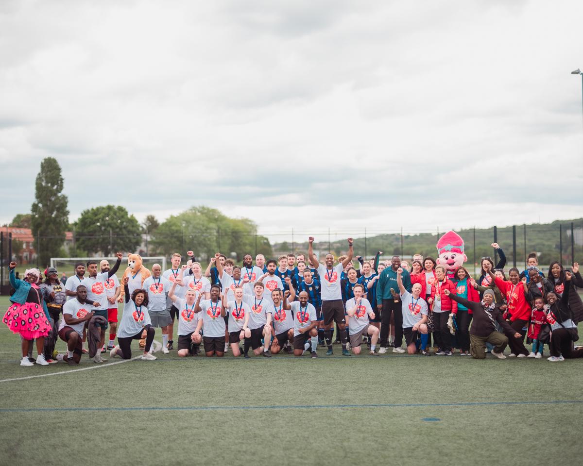 Group of people including two football squads celebrating in group shot