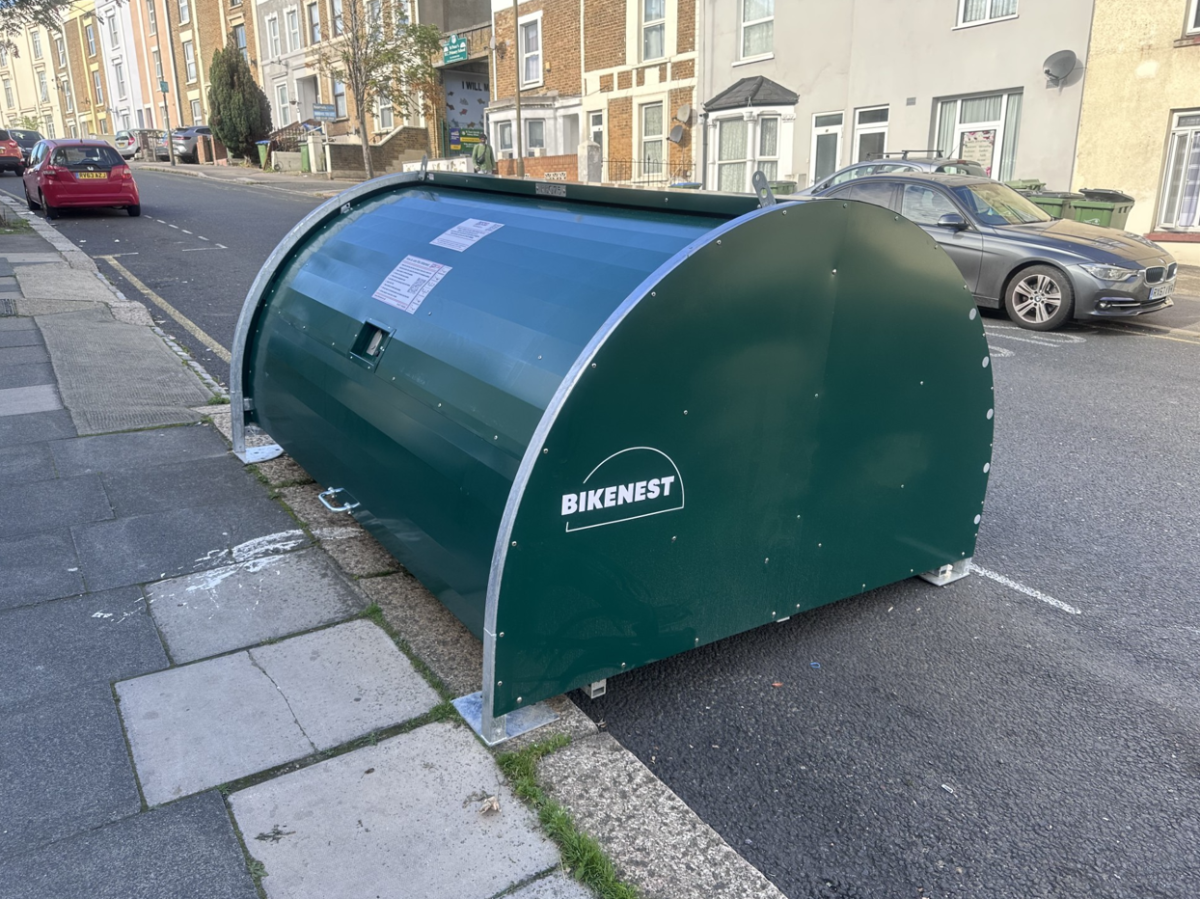 On-street dark green cycle hanger, picture shows houses in the background 