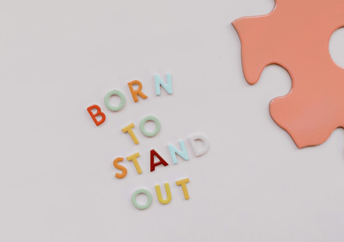 magnet letters on a white piece of card spelling out in capital letters BORN TO STAND OUT