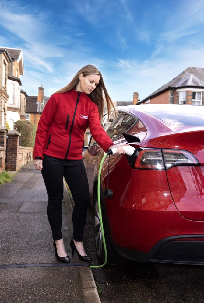a person charging their car with a cross-pavement channel 