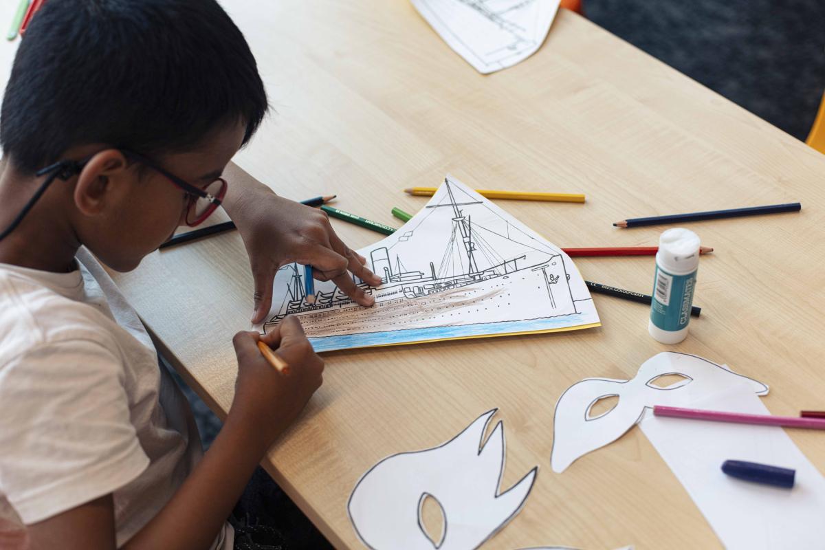 A child colouring in a picture of HMS Windrush