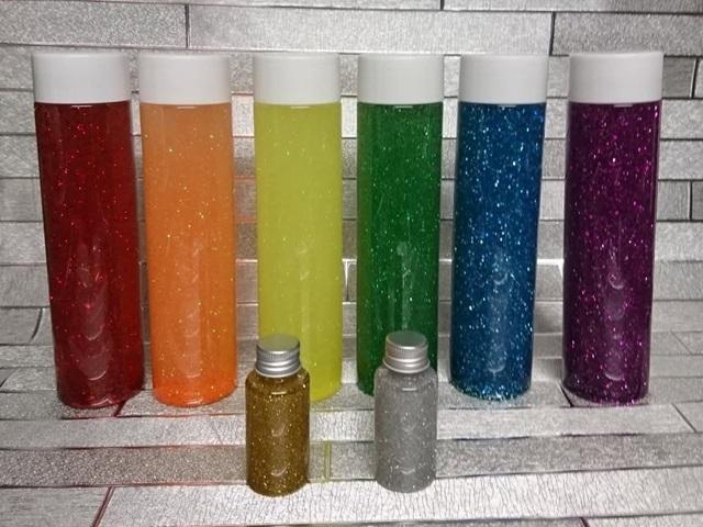 6 large and 2 small multi-colured sensory bottles in a line