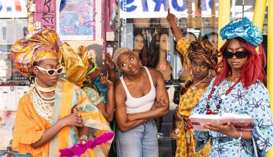 A group of women standing in front of a colourful shop front. 