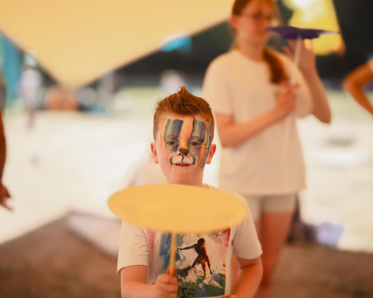Child spinning plates with face paint on his face