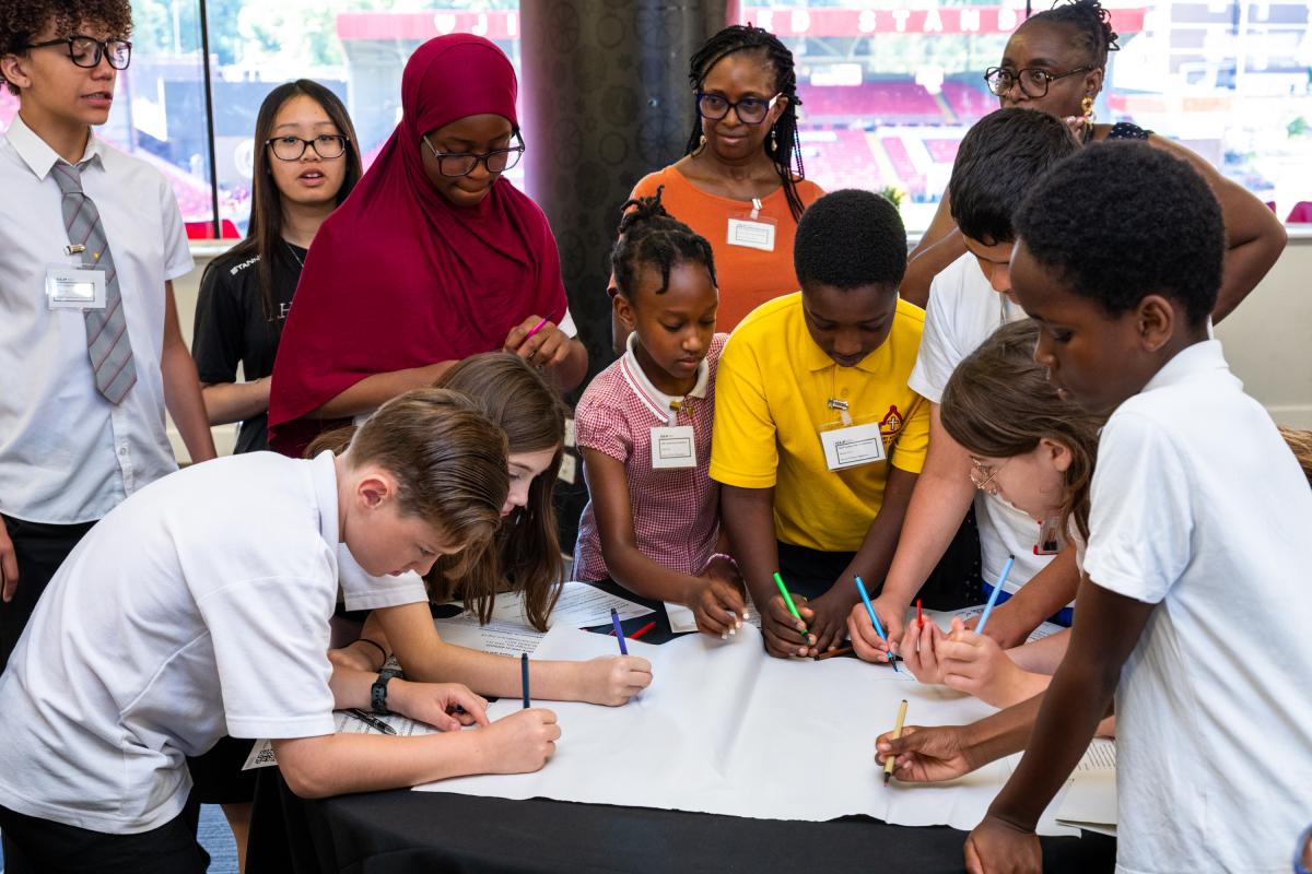 A group of young people around an activity holding pens to paper and sharing ideas for the borough